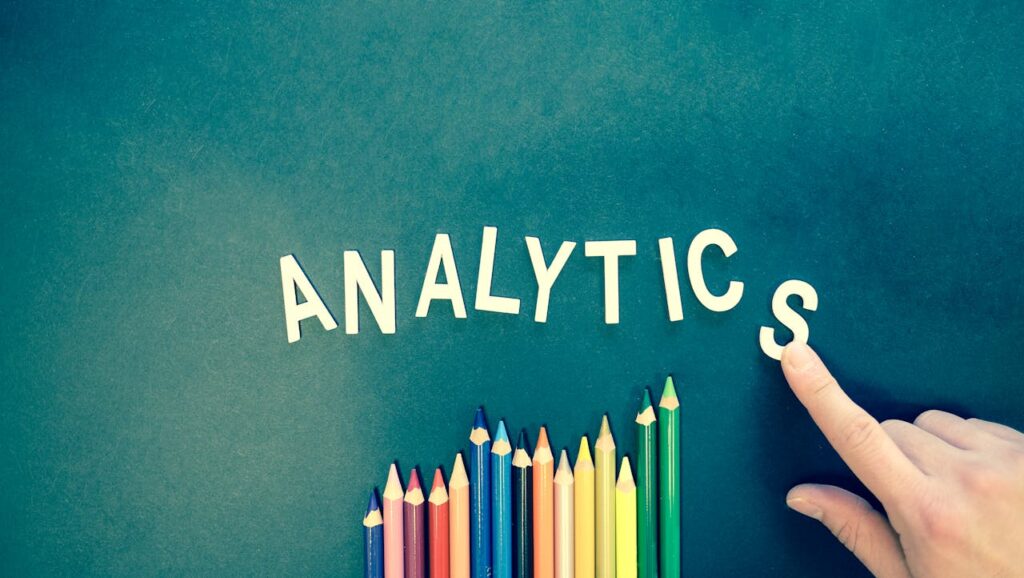 pexels-photo-185576 Colored pencils and letters spelling 'ANALYTICS' on a textured background with a hand.